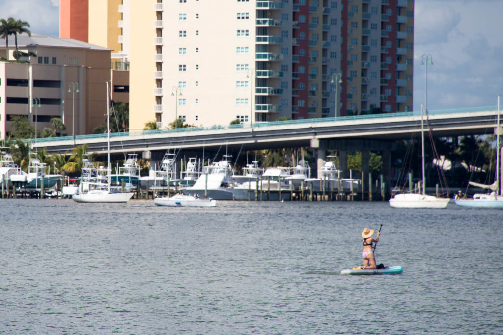 A woman on a paddle board in front of Blue Heron Bridge, near Peanut Island