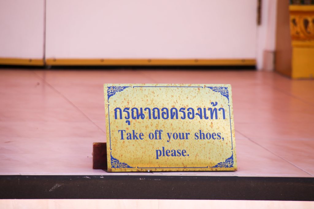 A sign asks visitors to remove their shoes before entering the Tampa Thai Temple