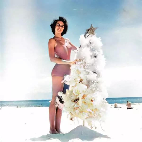 A woman decorates a Christmas tree on a beach in Florida