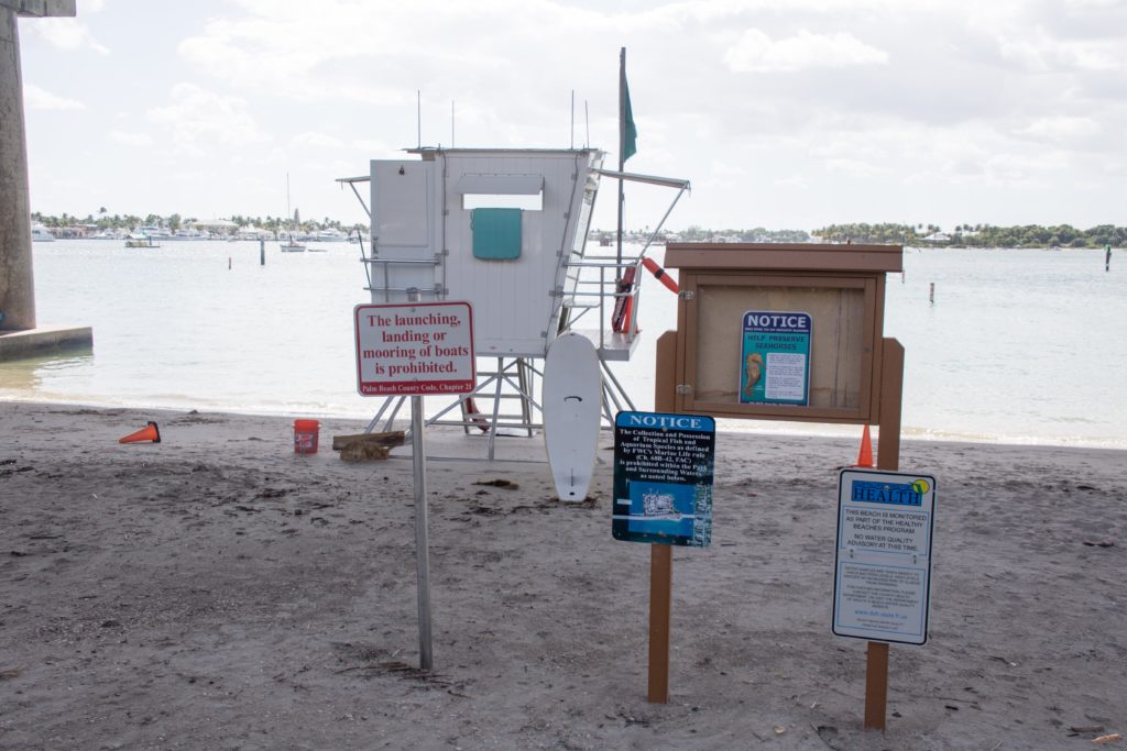 Phil Foster Snorkel Trail Rules in front of a lifeguard tower under the Blue Heron Bridge