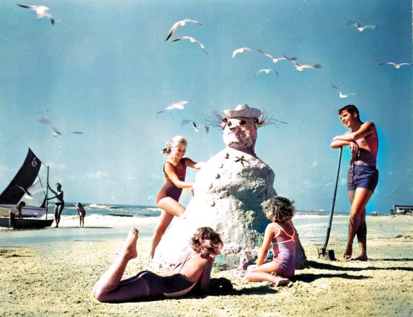 A family builds a snowman out of sand on a beach in Florida